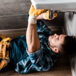 selective focus of repairman fixing water damage in bathroom